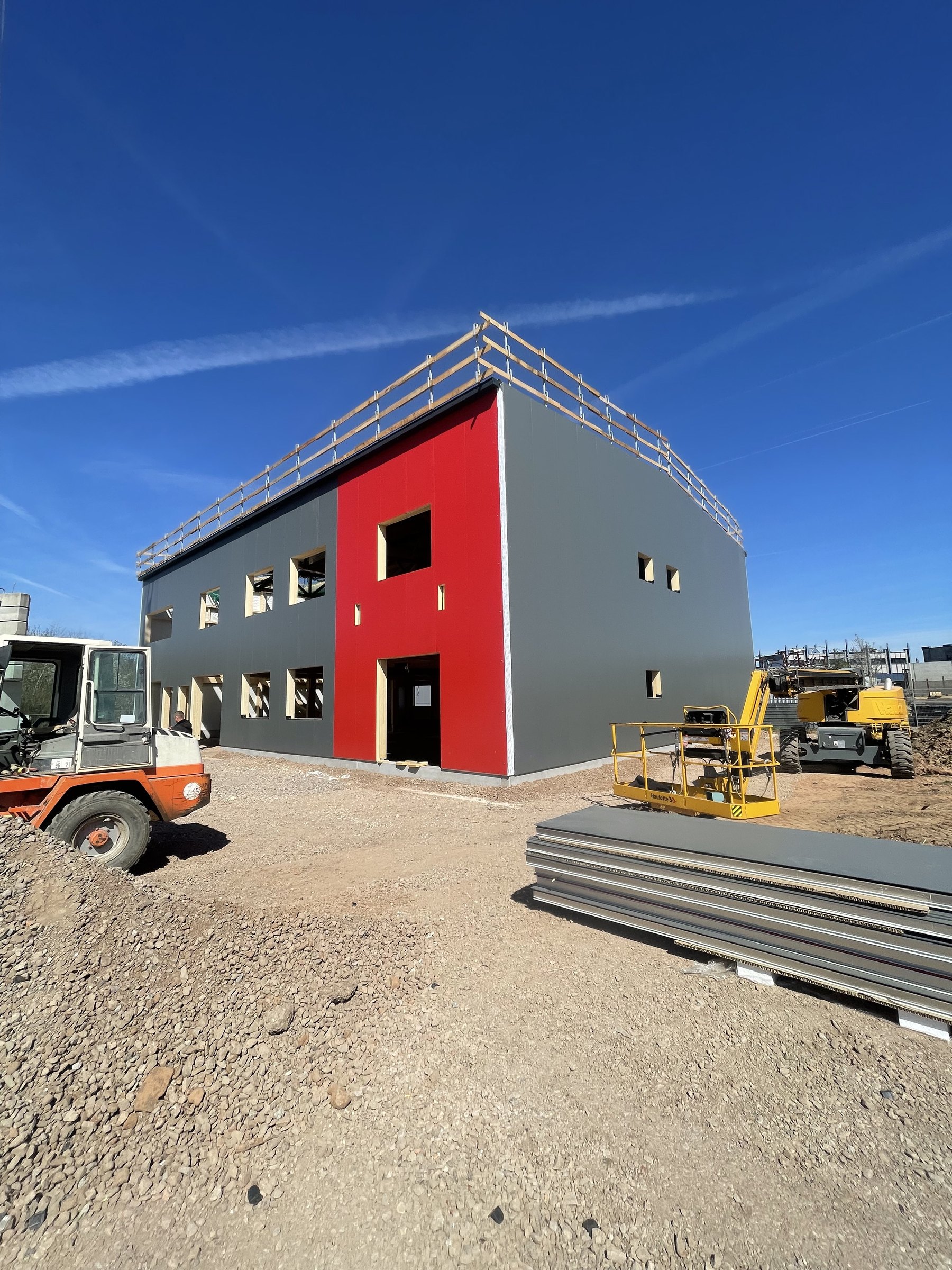 Anthracite and red sandwich-panel façade nearing completion