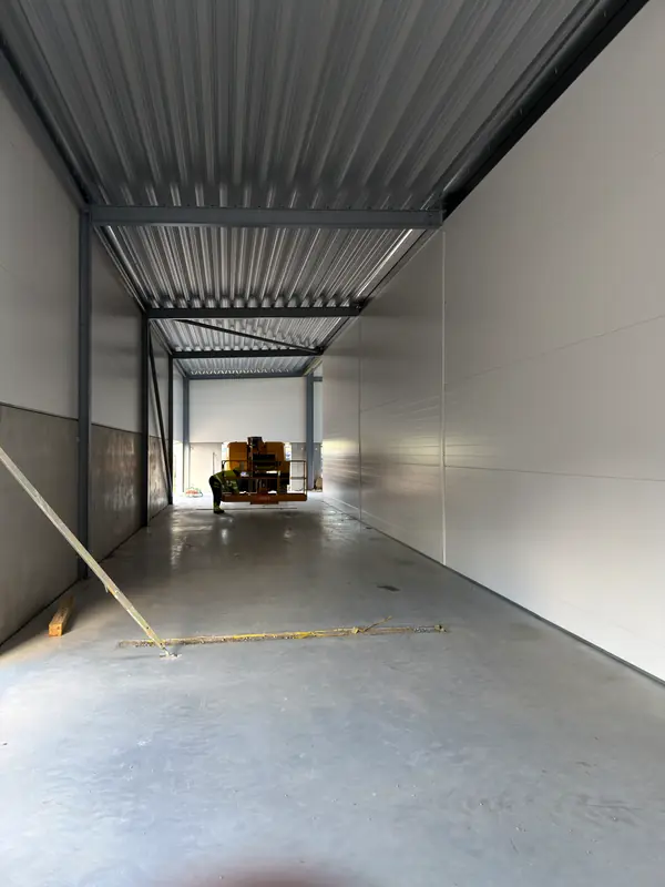 Long internal passage enclosed with white sandwich panels and profiled roof deck