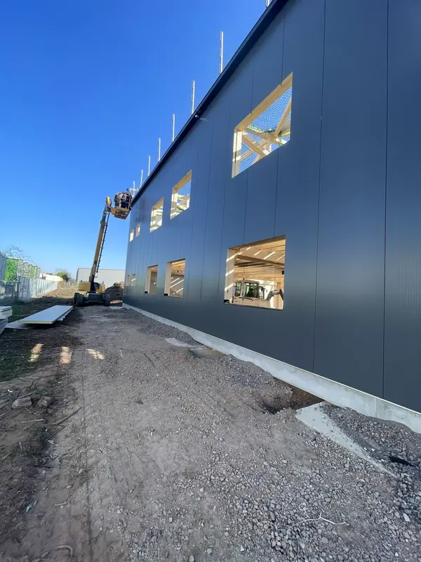 Long anthracite sandwich-panel façade during installation