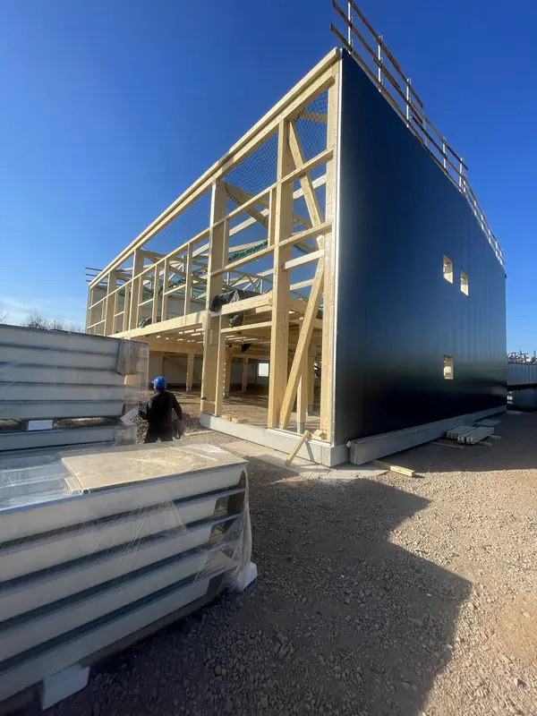 Sandwich-panel enclosure meeting the steel and timber structure