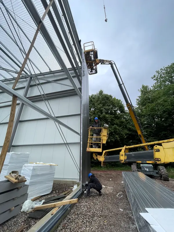 Sandwich wall panels being installed on the warehouse steel frame